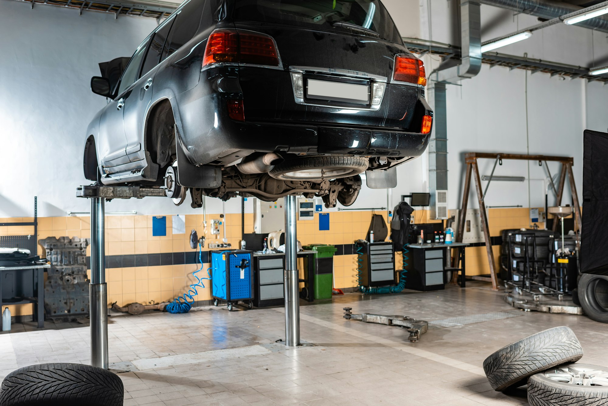 modern black car raised on car lift in workshop